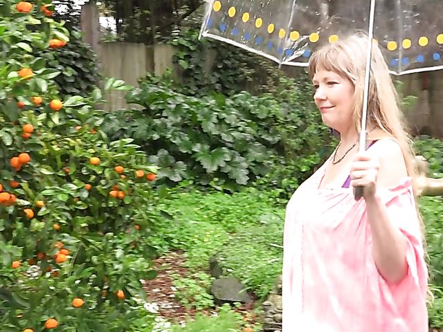 Flirty mature woman shows her boobs in the garden on a rainy day and masturbates at home