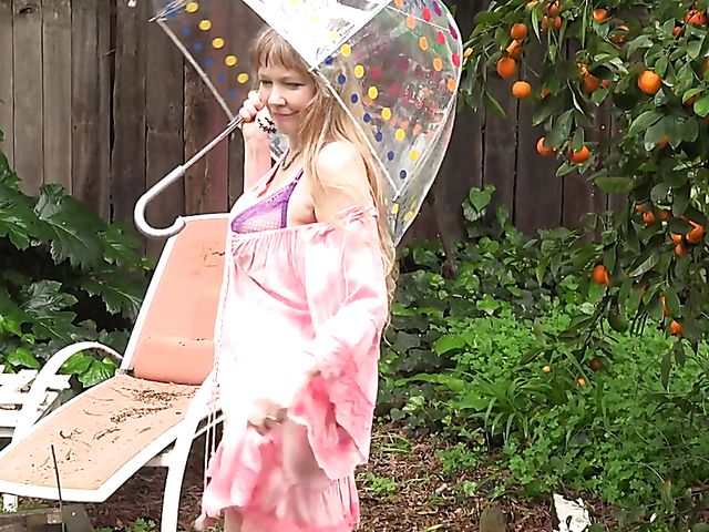 Flirty mature woman shows her boobs in the garden on a rainy day and masturbates at home