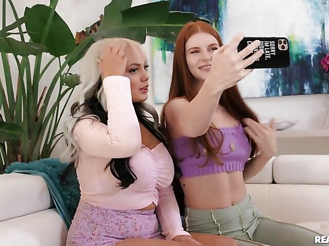 Redhead lesbian Jane Rogers kissing and licking busty Nika Venom on the sofa