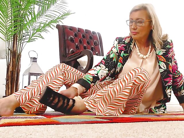 Shaved mature woman with glasses gets naked on the floor and pleasures herself